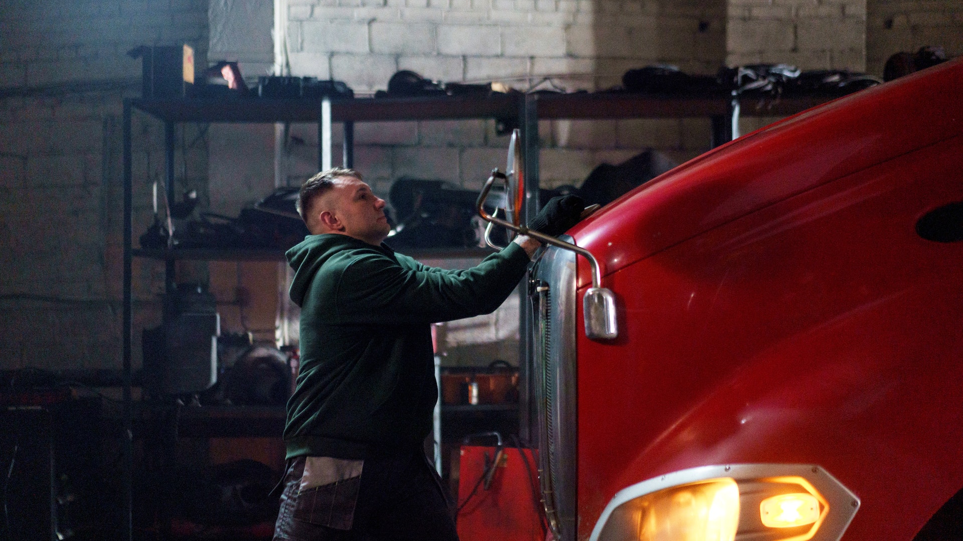 pexels-cottonbro-studio-7019612 Mechanic in green jacket holding tool working on red truck in garage