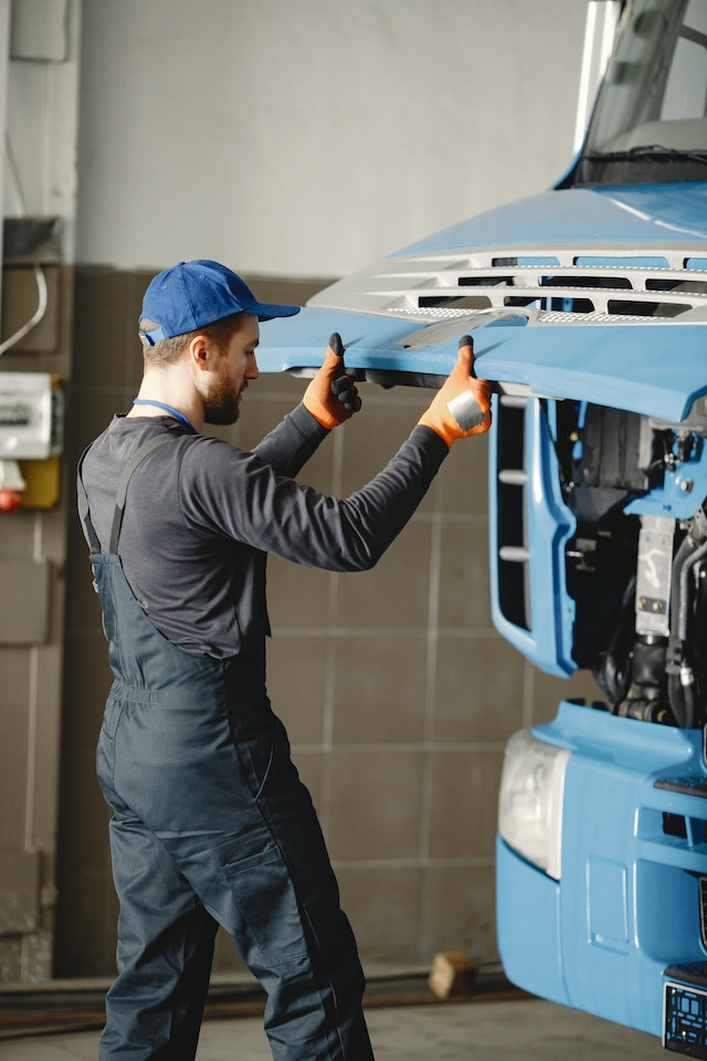 pexels-gustavo-fring-6720536 A mechanic in orange gloves working on a blue truck in a garage